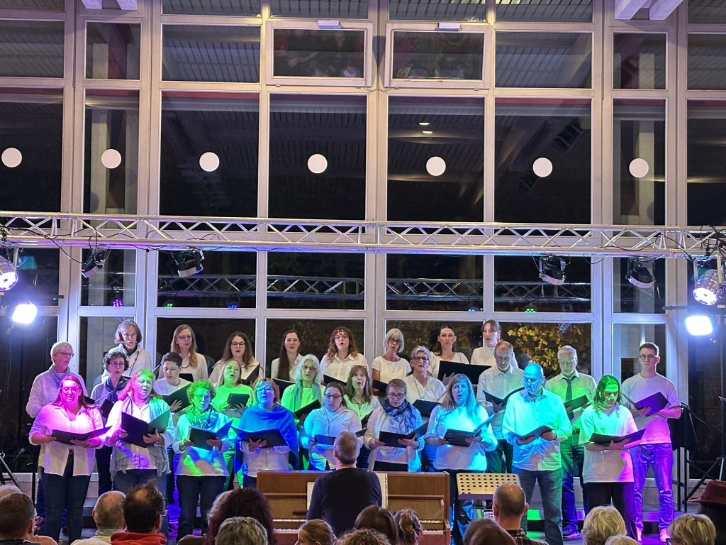 Ein Foto zeigt den PopChor des Sängerhains Grünwettersbach auf der Bühne beim Treffen moderner Chöre in Auerbach am 25.10.2025.